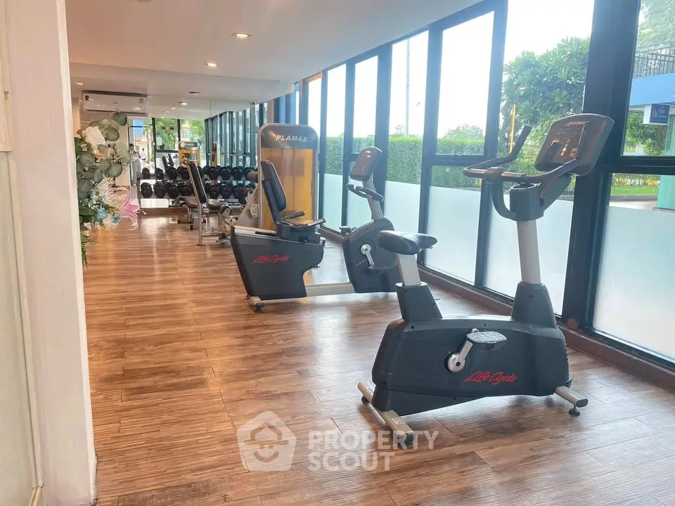 Modern gym with exercise bikes and weights in a bright, spacious room with large windows.