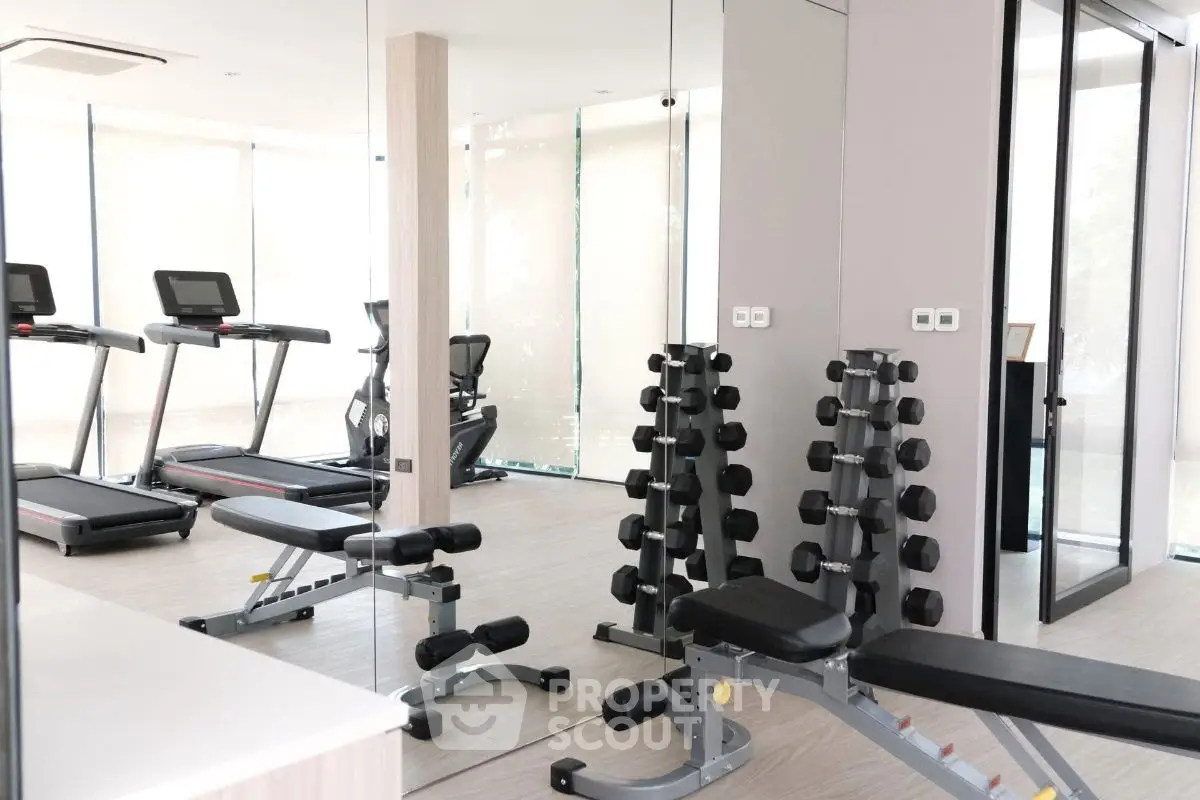 Modern gym with treadmills and weight benches in a bright fitness room.