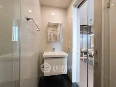 Modern bathroom with sleek design and sliding door leading to a stylish living area.