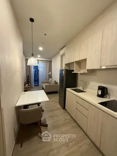 Modern kitchen with open layout and cozy living area, featuring sleek cabinetry and contemporary lighting.