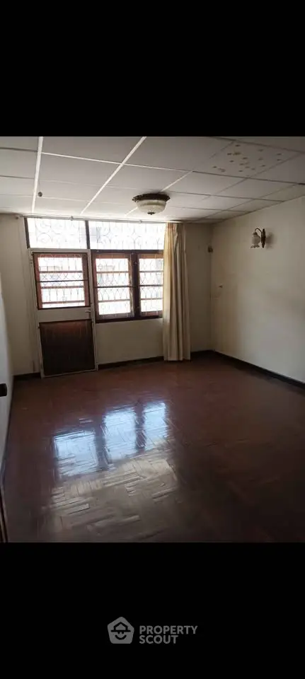 Spacious empty room with wooden flooring and large windows, ideal for customization.