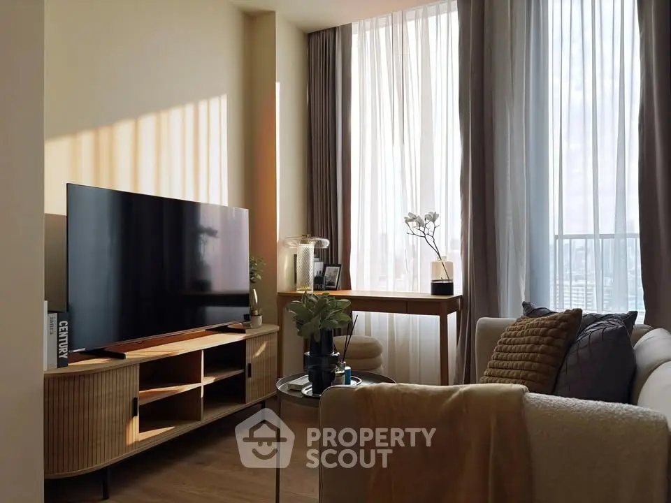 Modern living room with large TV, stylish furniture, and floor-to-ceiling windows offering natural light.
