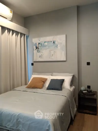 Cozy bedroom with modern decor and abstract art, featuring a comfortable bed and stylish side table.
