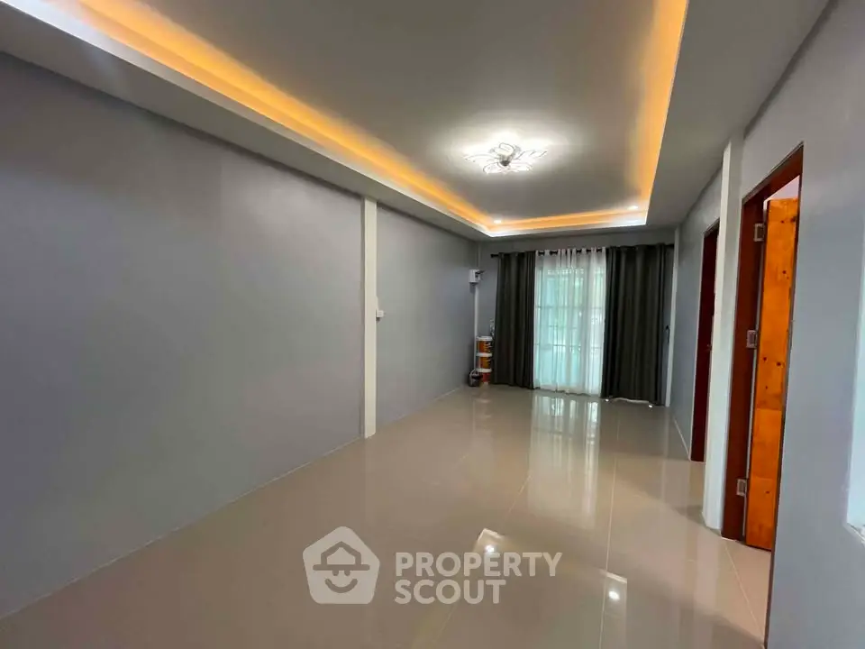 Spacious modern living room with sleek flooring and ambient lighting, perfect for contemporary living.