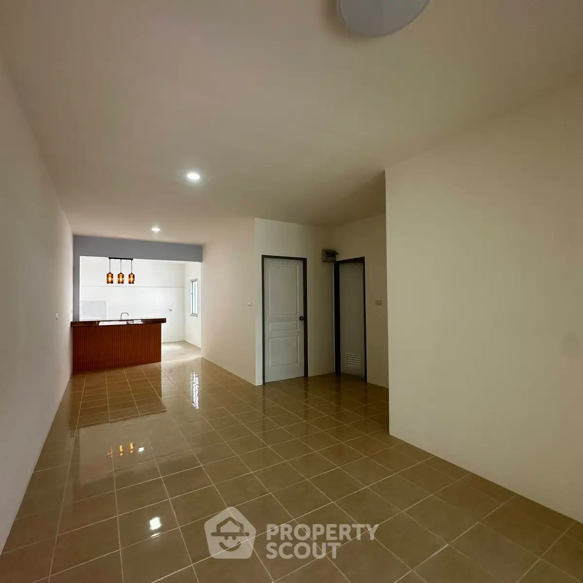 Spacious open-plan living area with tiled flooring and modern kitchen