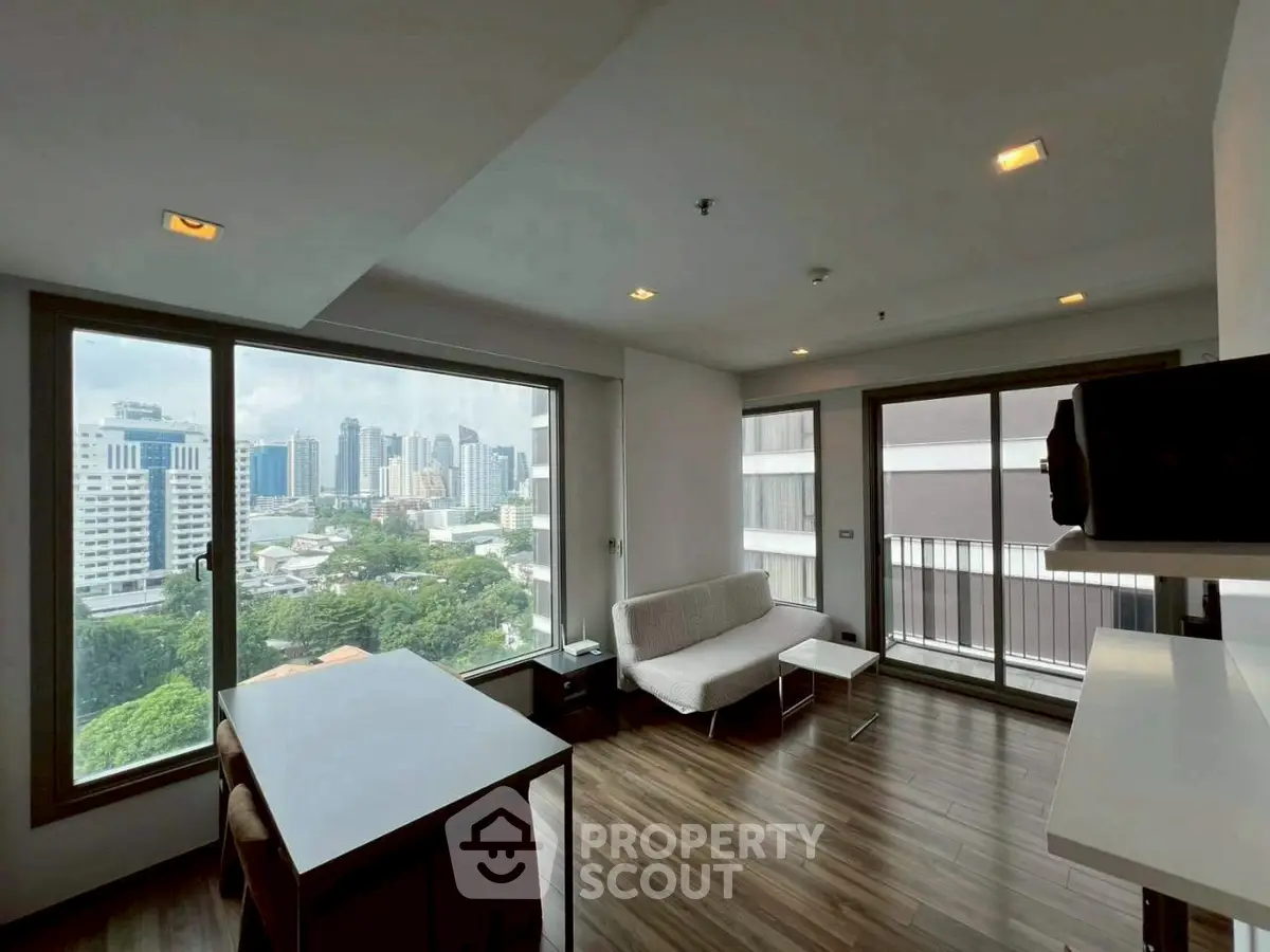 Modern living room with city view and large windows in high-rise apartment.