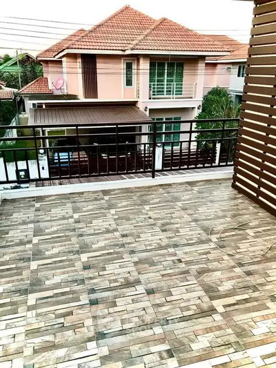 Spacious balcony with tiled flooring overlooking a charming suburban house with red roof.