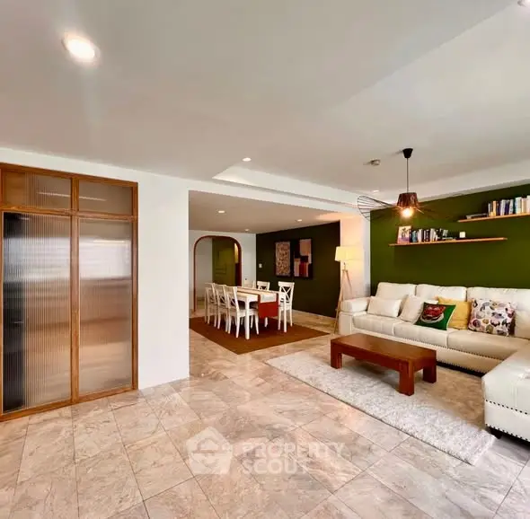 Spacious living room with elegant decor and dining area, featuring modern lighting and cozy seating.