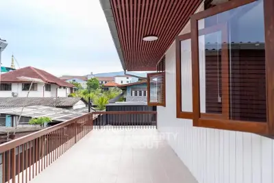 Spacious balcony with wooden accents and scenic neighborhood view, perfect for relaxation.