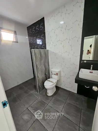 Modern bathroom with sleek tiles and compact design, featuring a toilet and sink.