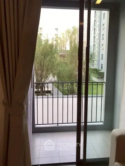 Cozy apartment balcony with serene garden view and sliding glass doors.