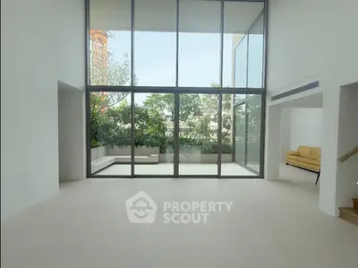 Spacious modern living room with floor-to-ceiling windows and garden view