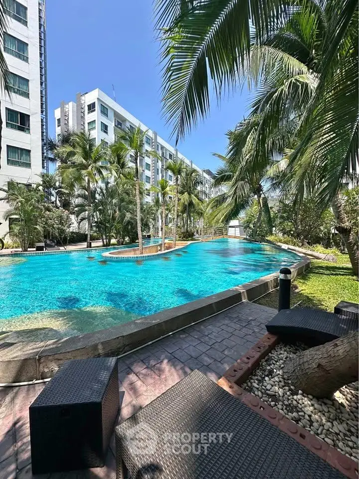 Luxurious residential pool area with palm trees and modern building backdrop.