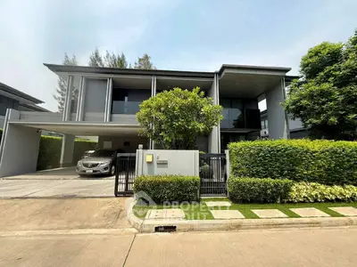 Modern two-story house with sleek design and lush greenery, featuring a spacious driveway and contemporary architecture.
