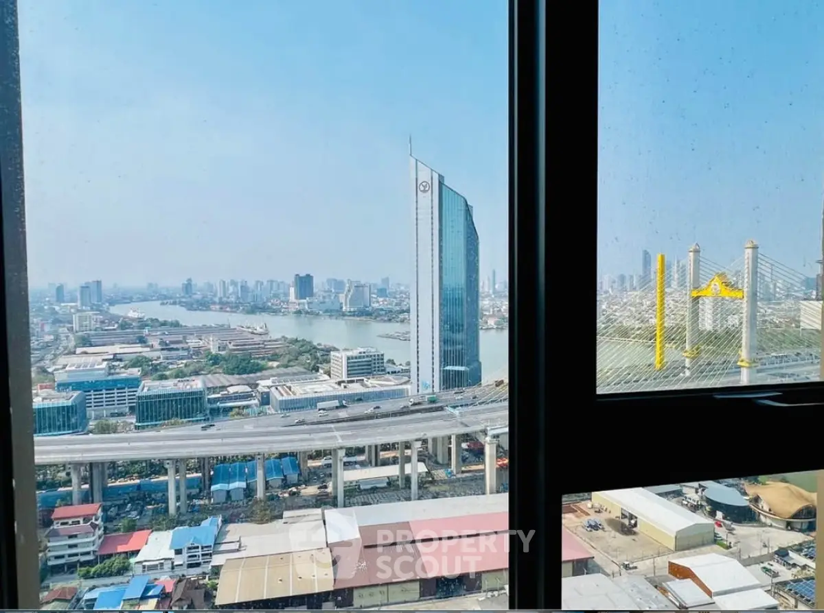 Stunning cityscape view from high-rise apartment window overlooking river and skyline.
