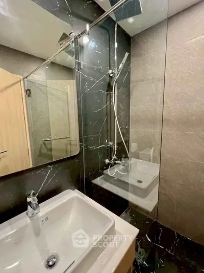 Modern bathroom with sleek black marble tiles and glass shower enclosure