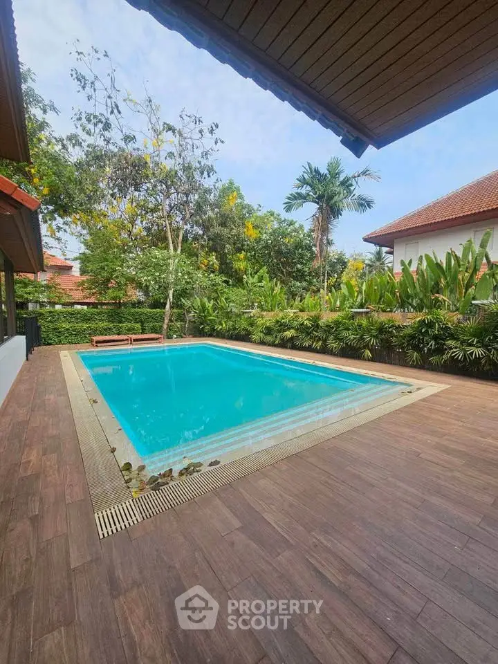 Luxurious private pool surrounded by lush greenery and elegant wooden deck, perfect for relaxation.