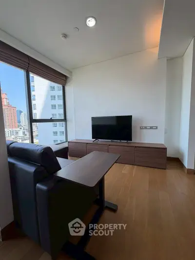 Modern living room with city view, featuring sleek furniture and large windows for natural light.