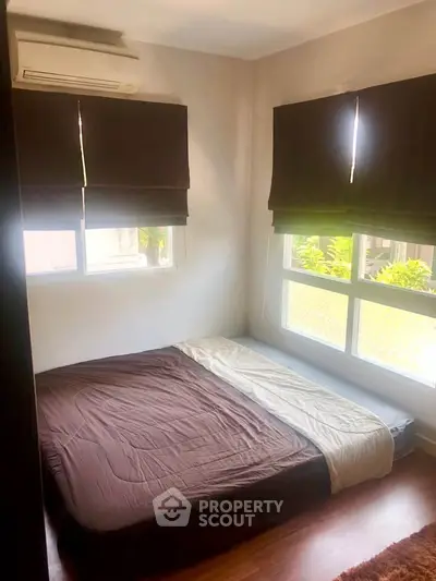 Cozy bedroom with large windows and air conditioning, featuring a minimalist design and natural light.