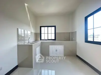 Bright minimalist kitchen with sleek countertops and large window, perfect for modern living.
