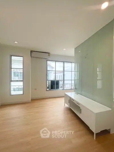 Spacious living room with large windows and modern air conditioning unit