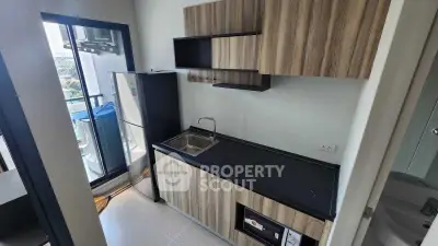 Modern compact kitchen with sleek wooden cabinets and balcony view