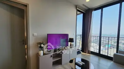 Modern living room with large windows offering stunning city views, featuring a sleek TV setup and elegant decor.