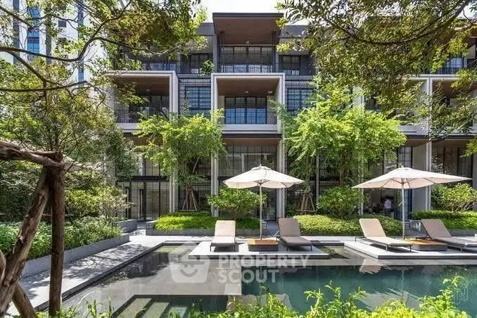 Luxurious modern apartment building with poolside lounge area and lush greenery.