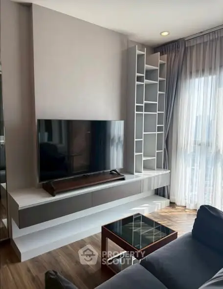 Modern living room with sleek TV unit and large window for natural light.