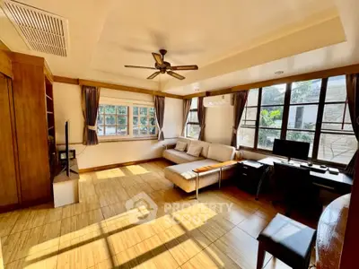 Spacious living room with natural light, wooden flooring, and modern furnishings.