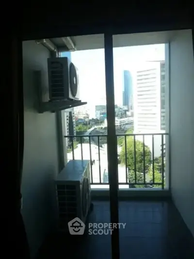 Compact balcony with city view and air conditioning units.