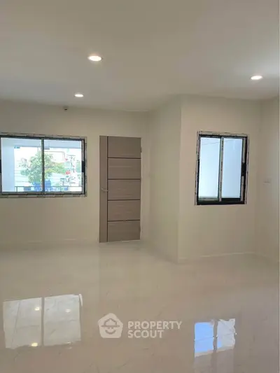 Spacious unfurnished room with large windows and glossy tiled floor, perfect for customization.