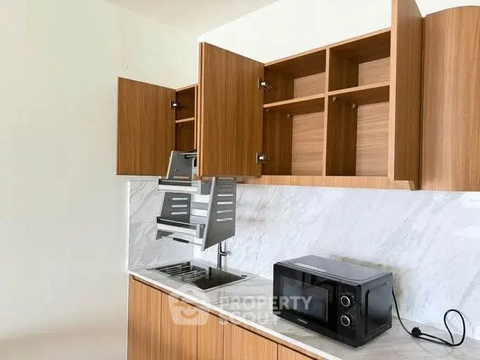 Modern kitchen with sleek wooden cabinets and built-in microwave oven