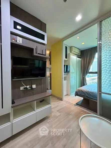 Modern apartment interior with open layout, featuring a cozy living area and a glimpse into the bedroom.