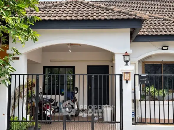 Charming single-story home with tiled roof and gated entrance, perfect for cozy living.