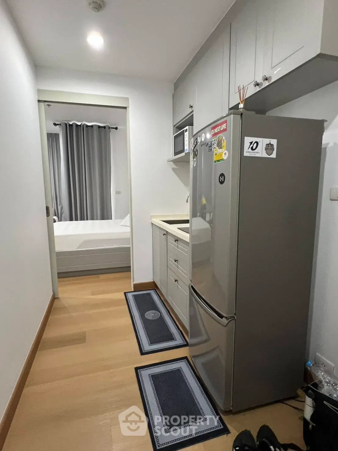 Compact kitchen with modern appliances leading to a cozy bedroom in a stylish apartment.