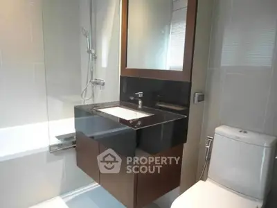 Modern bathroom with sleek fixtures and a glass-enclosed shower in a contemporary apartment.
