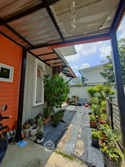 Charming garden entrance with potted plants and covered patio in a suburban home.