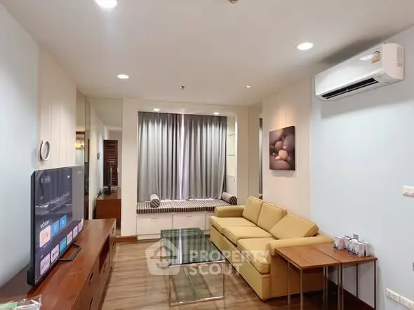 Modern living room with cozy sofa, glass coffee table, and wall-mounted TV in stylish apartment.