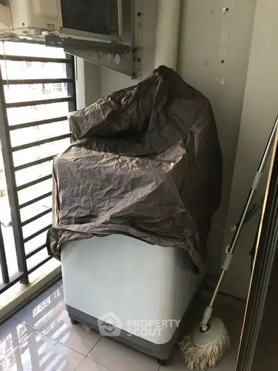 Compact balcony with washing machine and mop, ideal for urban living convenience.