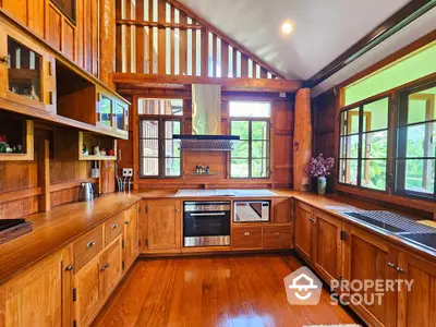 Stunning wooden kitchen with modern appliances and large windows offering natural light