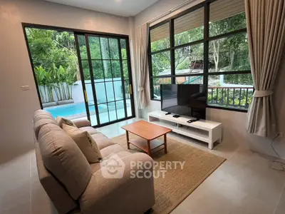 Charming living room with pool view, cozy sofa, and large windows in a serene setting.