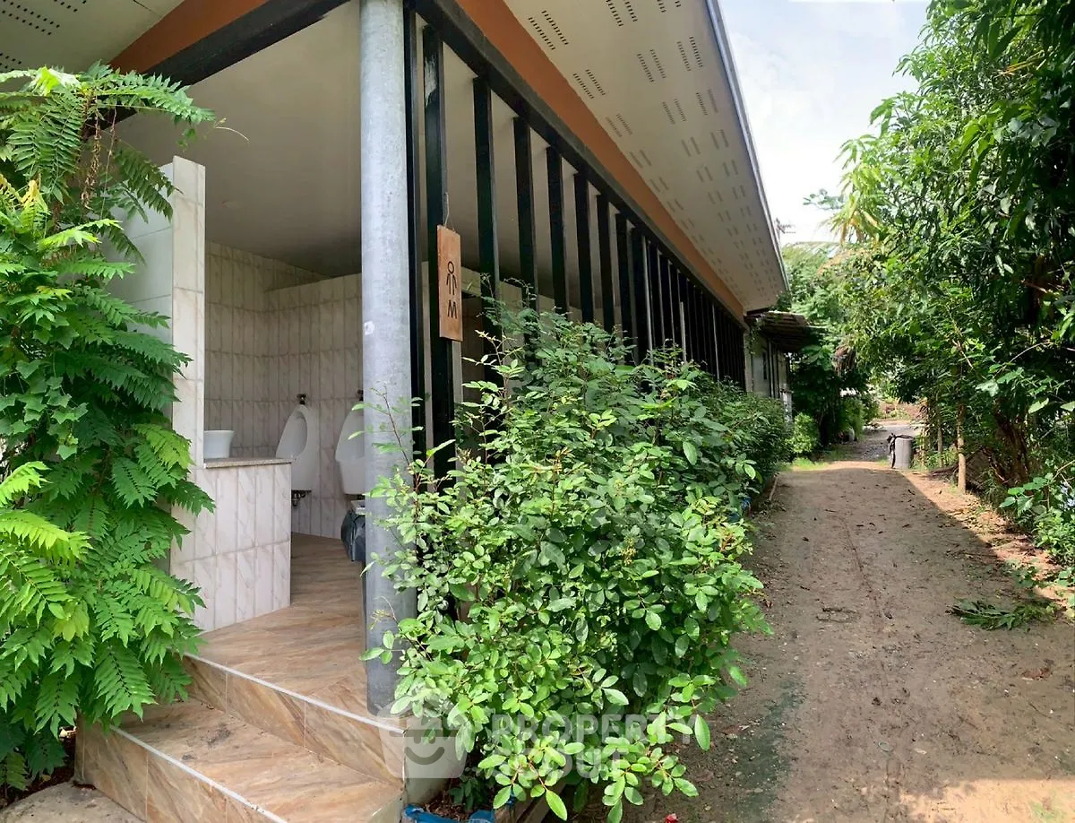 Charming outdoor restroom facility with lush greenery and tiled entrance.