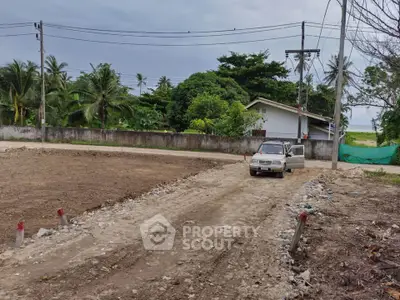Vacant land plot with dirt road access and lush greenery, ideal for development.