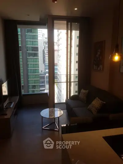 Modern living room with city view, stylish decor, and natural light in a high-rise apartment.
