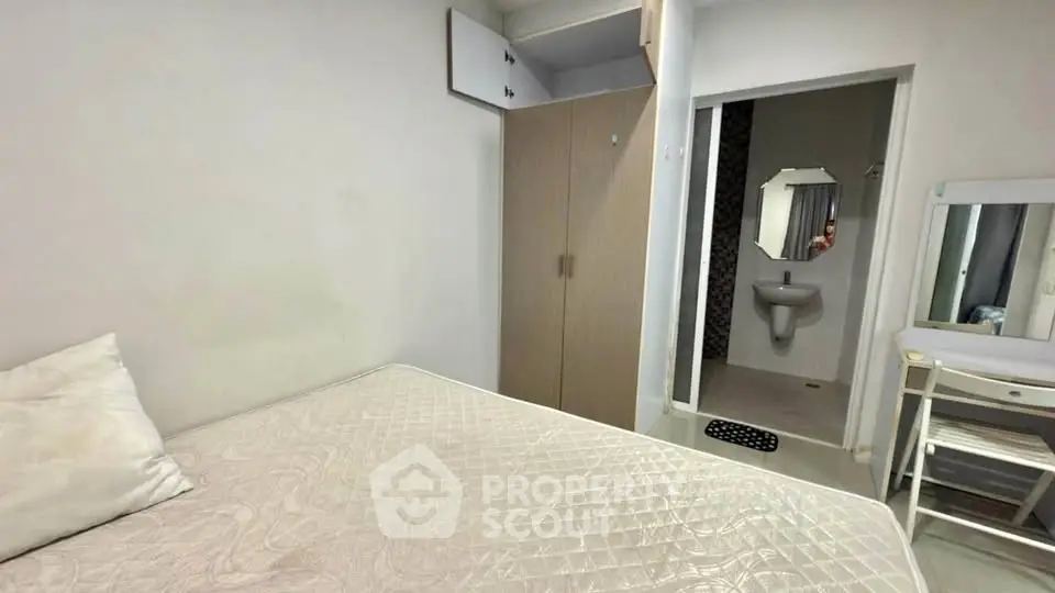 Cozy bedroom with ensuite bathroom and wardrobe in modern apartment.