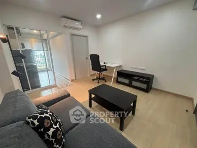 Modern living room with sleek furniture and wooden flooring, featuring a cozy workspace and stylish decor.