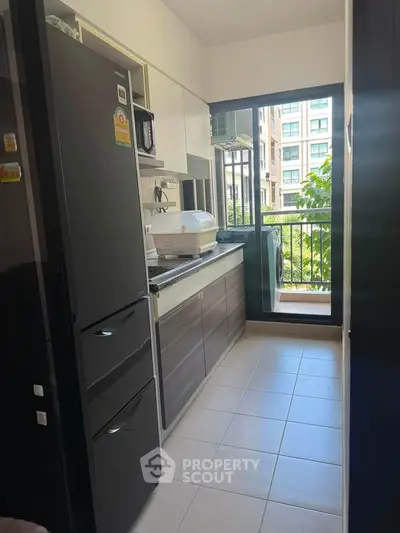 Modern kitchen with sleek cabinets and balcony view in urban apartment.