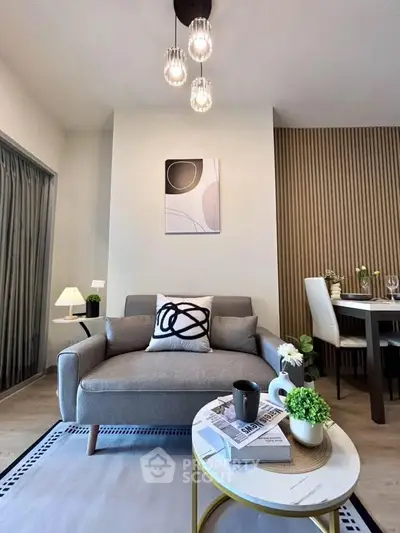 Modern living room with stylish decor and dining area, featuring elegant lighting and contemporary furniture.