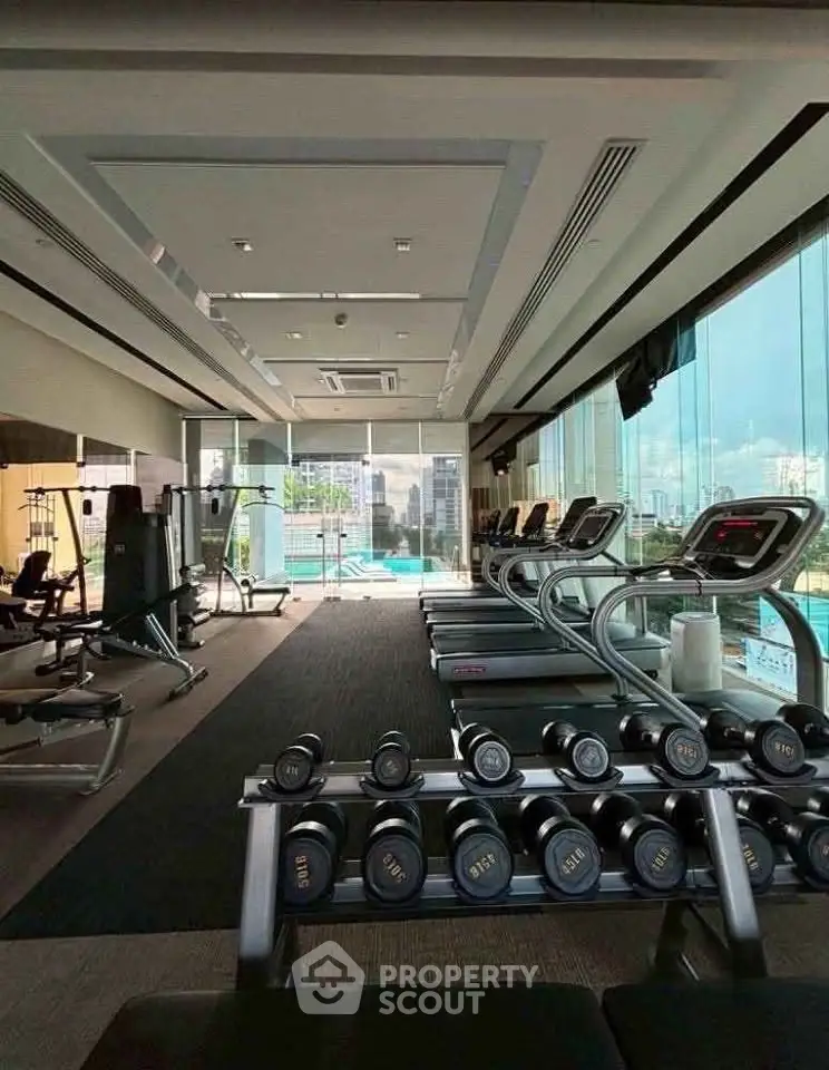 Modern gym with city view and state-of-the-art equipment in luxury building.